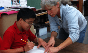 teacher helping student at desk